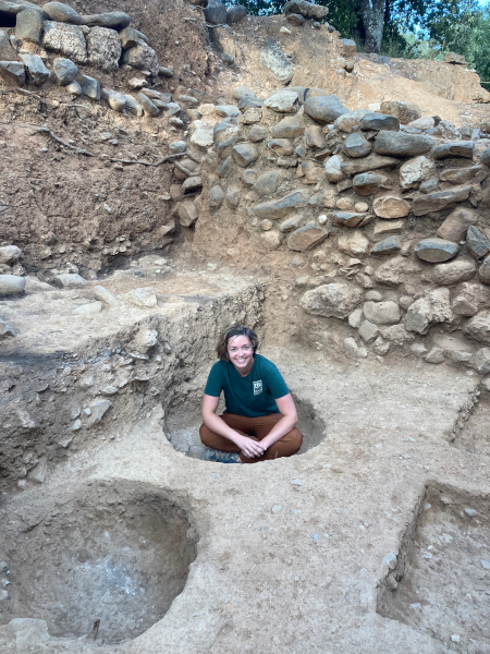A picture of me from the 2022 excavation season, featuring some of the pits which we did not miss. Photo credit: Sarah Harrington.